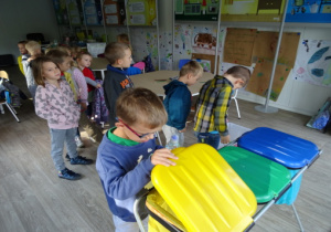 Dzieci wrzucają odpady do odpowiedniego pojemnika.